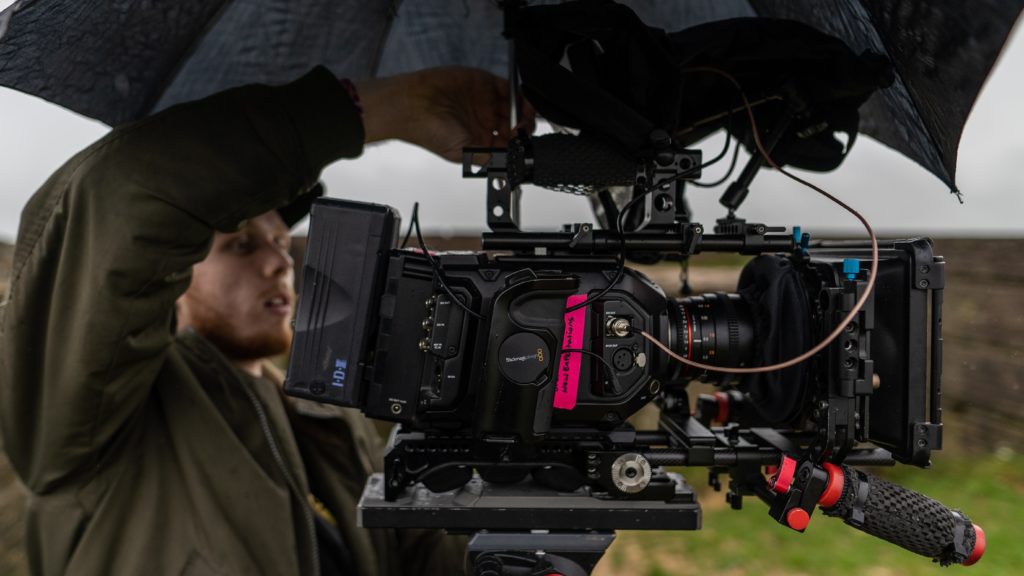 A man directing a film outdoors, standing by a camera