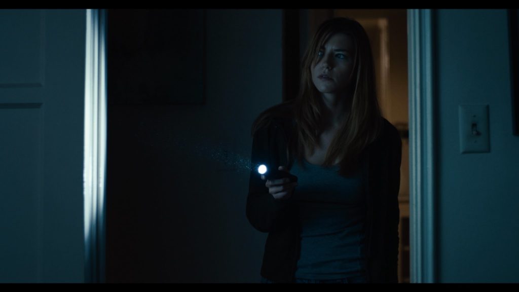 A woman holding a flashlight in a dark room - a still image from 'the thing in the apartment'