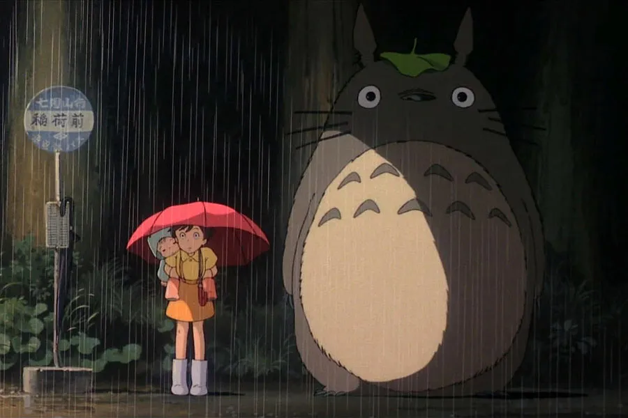 Totoro at a bus stop with the two main characters from My Neighbor Totoro.
