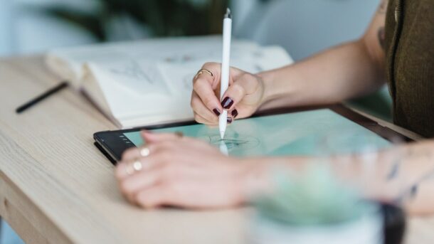 An artist sitting in front of a tablet and using it to draw.