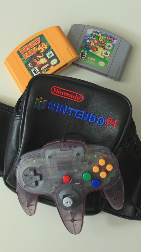 A Nintendo 64 controller and carrying case alongside the cartridges for Donkey Kong 64 and Super Mario 64.