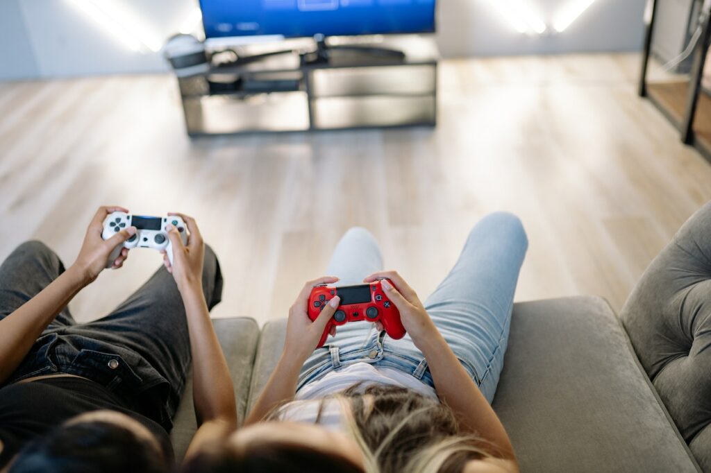 Two people sitting on a couch playing video games on their Playstation 4.