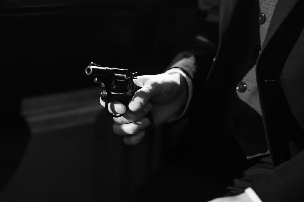 A film noir scene of a close-up of a man holding a gun.