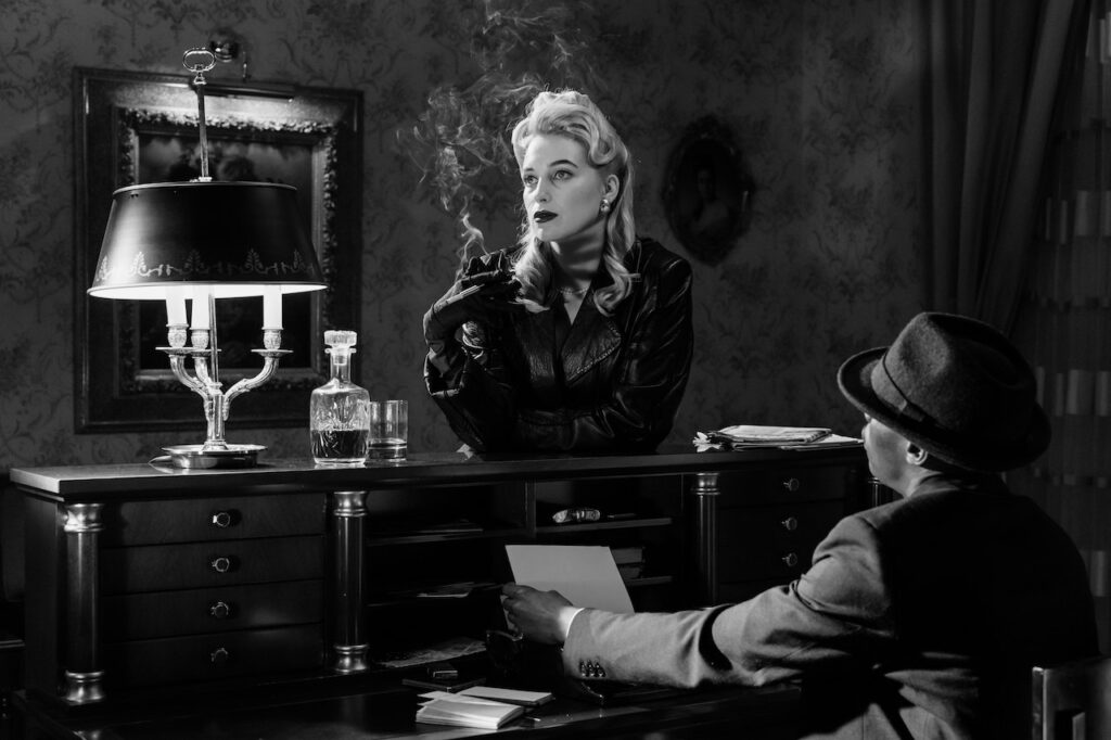 A noir film scene of a man and woman drinking and smoking together.