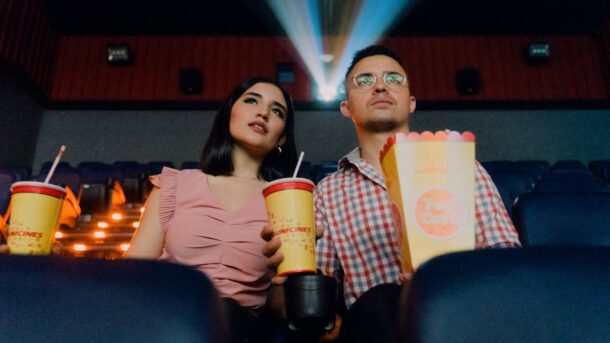 A couple watching a movie trailer in a theatre.