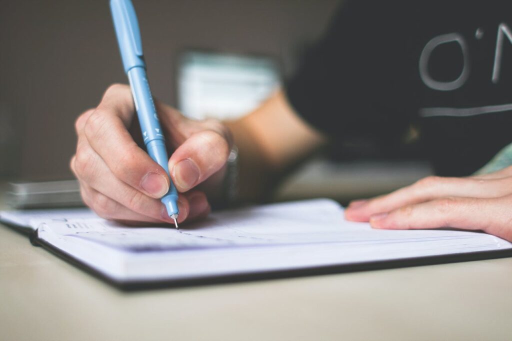 A person writing a script in their notebook.