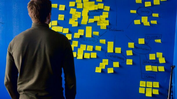 A person brainstorming a variety of topics using sticky notes.